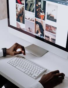 Man working on computer in modern office, viewing photography website. Clean and tech-focused environment.
